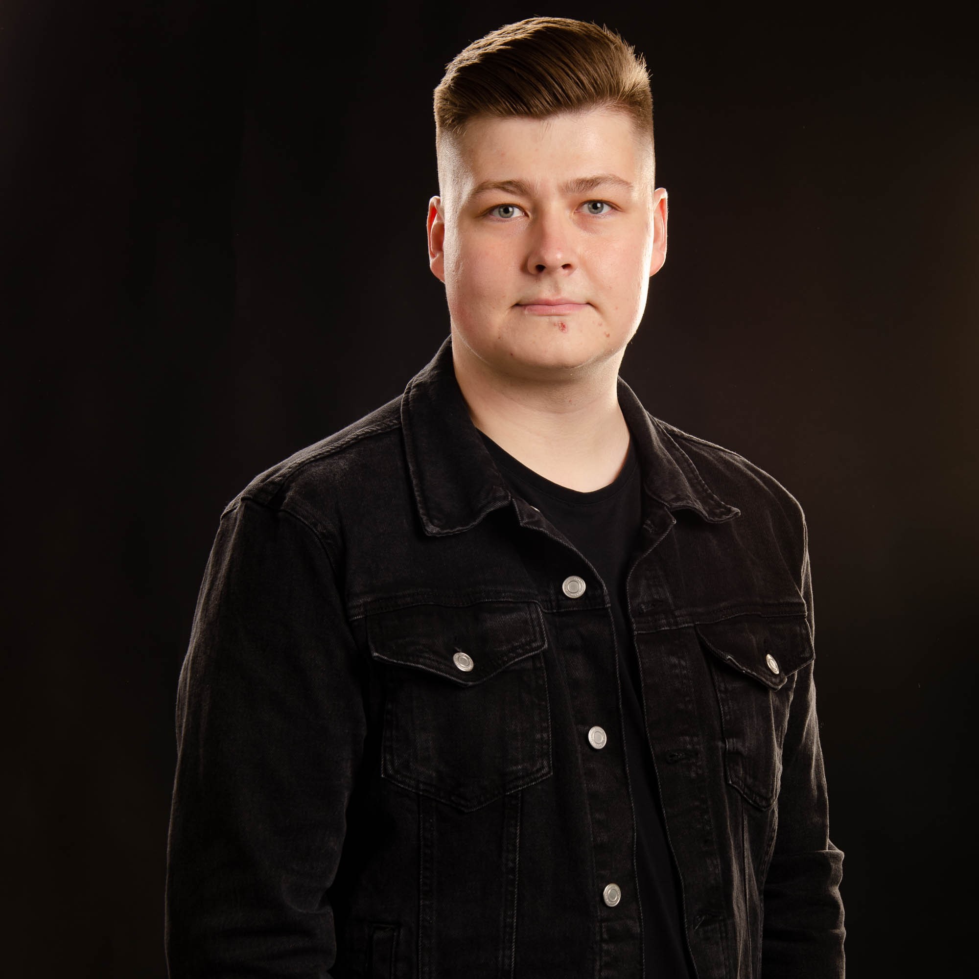 Eeli Arola tummassa farkkutakissa mustaa taustaa vasten